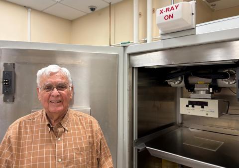 Mitchell stands in front of a large stainless-steel lab instrument.