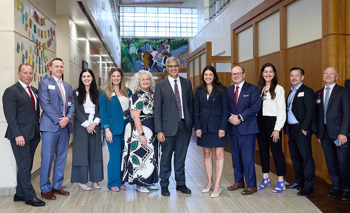 Large group poses together in colorful building with big windows